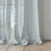Sheer white curtains with a subtle pattern hanging in front of a window.
