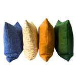 Four decorative throw pillows in blue, cream, mustard yellow, and green, each featuring a unique geometric line pattern, arranged in a row against a plain white background.