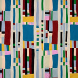 An abstract geometric textile or wall hanging with vertical bands of colored rectangular blocks on a light neutral background. The pattern includes blue, red, green, yellow, pink, black, and cream tones.