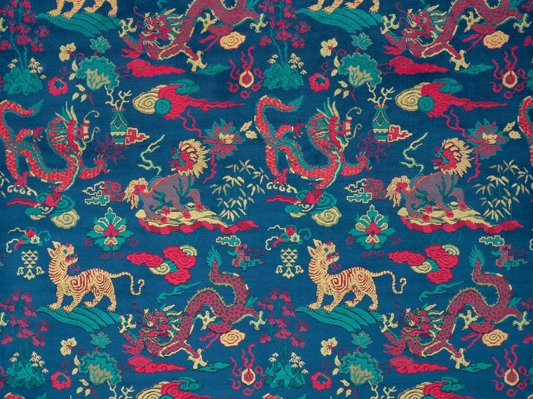 A close-up of a fabric pattern featuring traditional Chinese-style motifs, including red dragons, golden lions, and green foliage, all set against a deep teal-blue background.