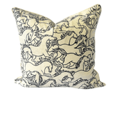 A square decorative throw pillow featuring a black line art print of running horses on a warm cream fabric background, shown against a plain white background.
