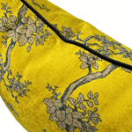 A close-up of a gold fabric product, likely a cushion cover or pillow, featuring a woven floral pattern in beige and gray with a black piping border.
