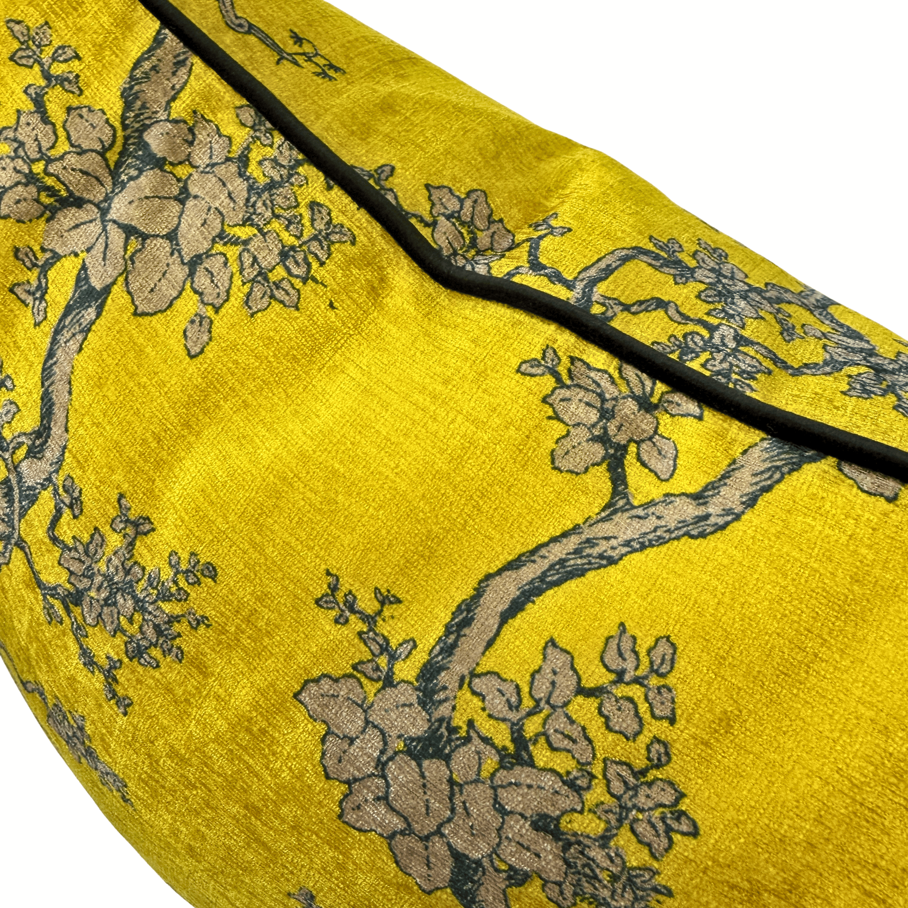 A close-up of a gold fabric product, likely a cushion cover or pillow, featuring a woven floral pattern in beige and gray with a black piping border.