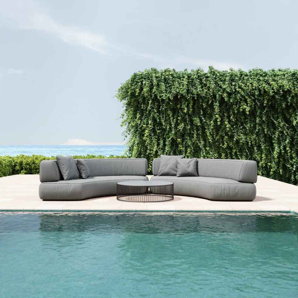 Gray outdoor sectional sofa by a pool with greenery in the background
