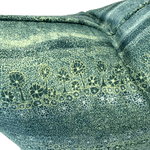 A close-up of textured fabric with a dark green base covered in fine light yellow-green dots, overlaid with a row of stylized tree silhouettes in dark green outlined with pale yellow lines.