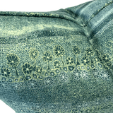 A close-up of textured fabric with a dark green base covered in fine light yellow-green dots, overlaid with a row of stylized tree silhouettes in dark green outlined with pale yellow lines.
