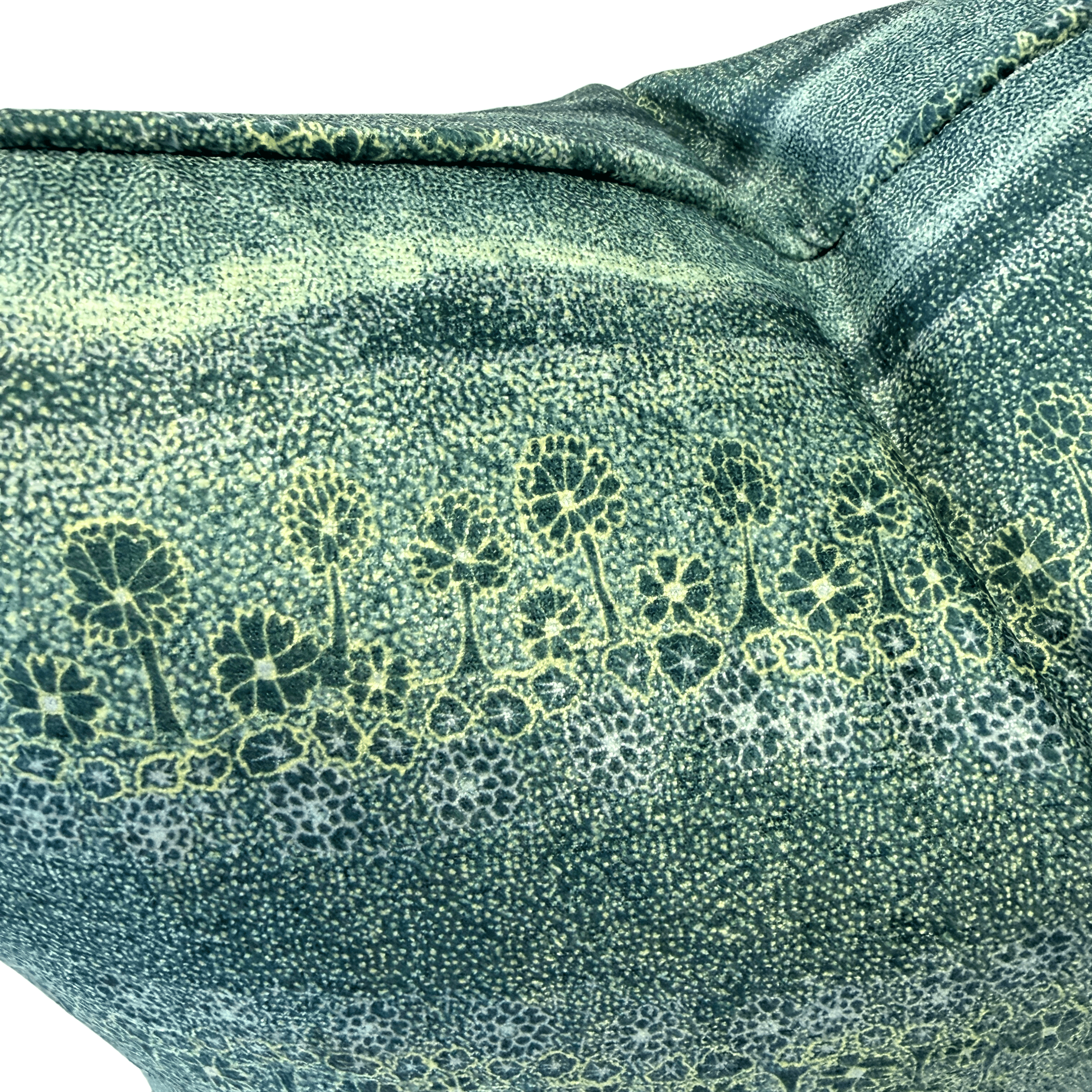 A close-up of textured fabric with a dark green base covered in fine light yellow-green dots, overlaid with a row of stylized tree silhouettes in dark green outlined with pale yellow lines.