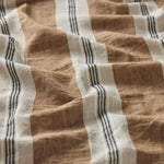 A close-up of a textured woven fabric with vertical stripes in warm brown, off-white, and dark charcoal gray.