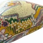 A close-up of a decorative throw pillow featuring a vibrant, multicolored botanical and abstract pattern on a cream-colored fabric background.